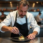 Chef étoilé en train de dresser une assiette de gastronomie française dans une cuisine de restaurant haut de gamme